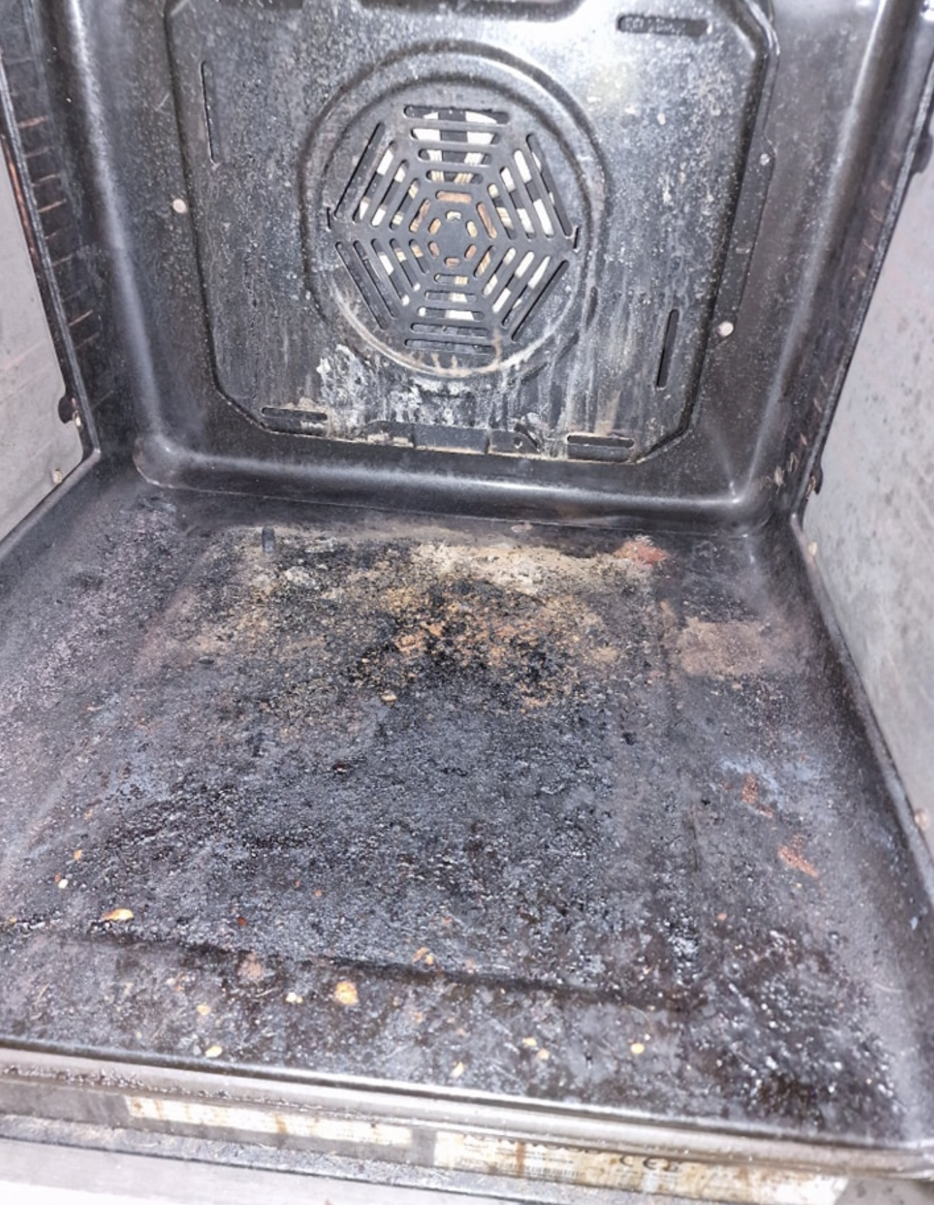 Oven interior before cleaning — thick carbon and burnt-on debris